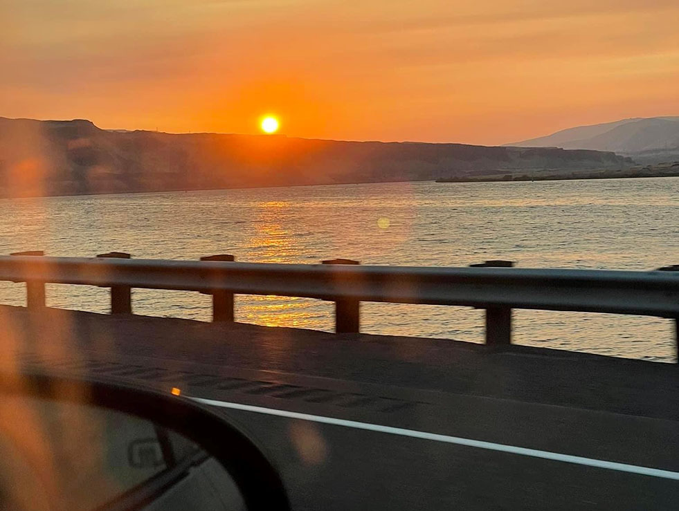 View of sunset over water from a car window