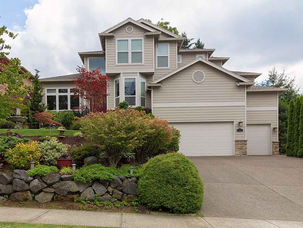 Traditional tan house in suburbs with green lawn