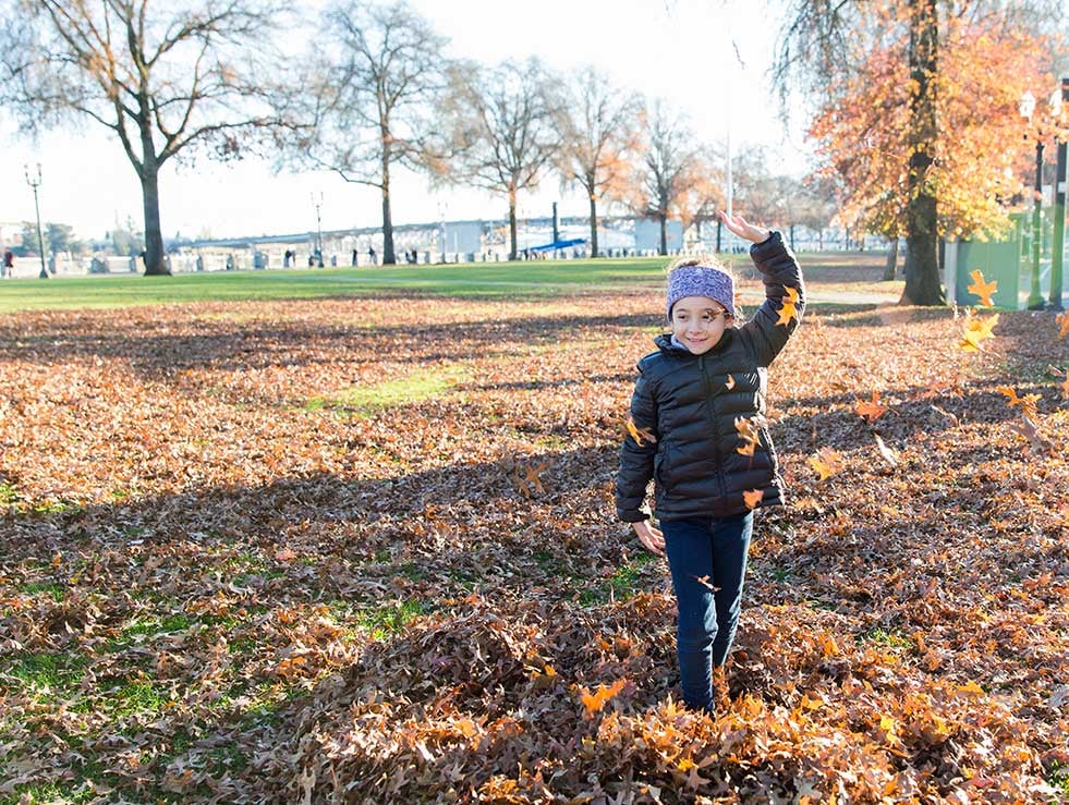 Girl playing in autumn leaves